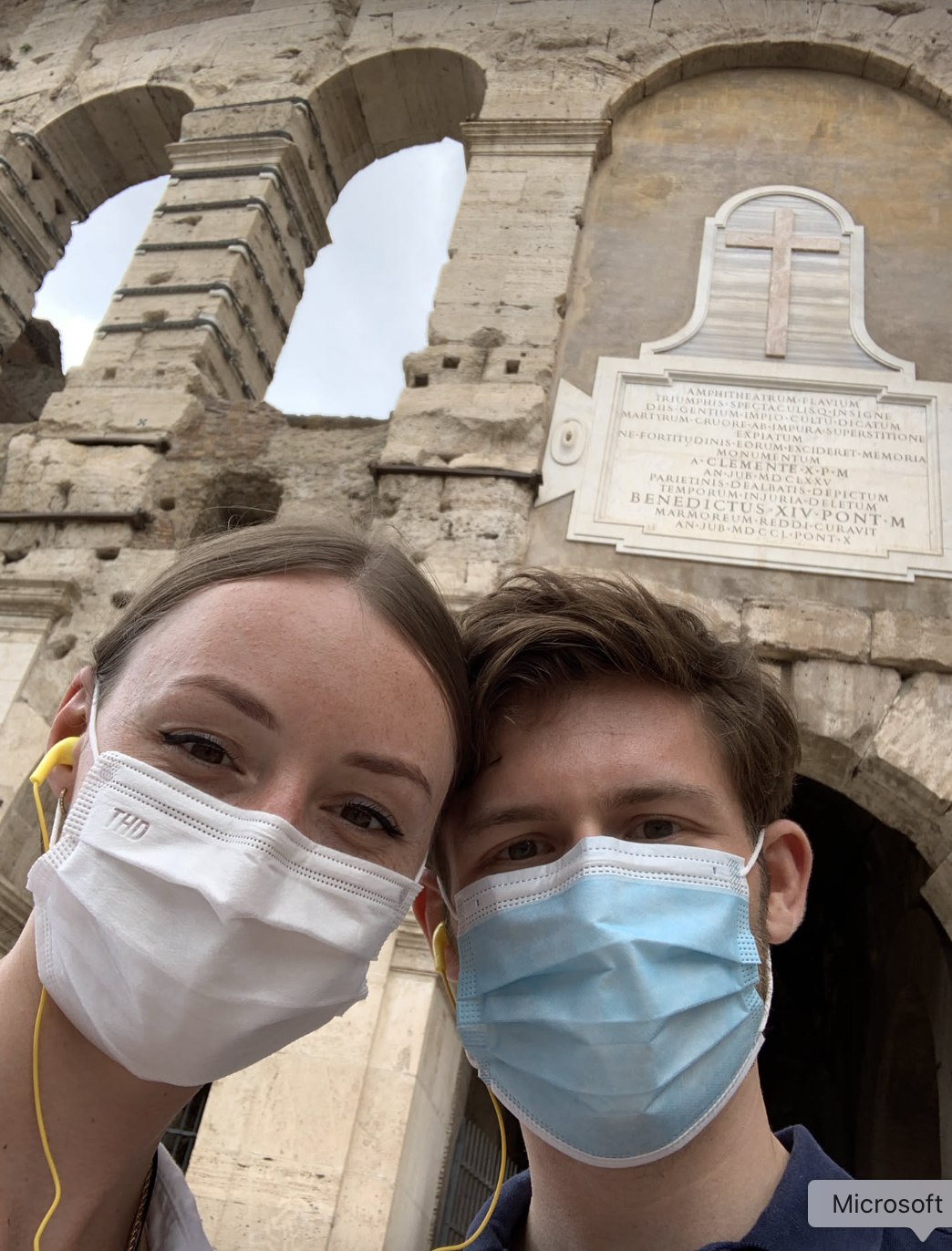 Leonard and Mona in front of the Colosseum in Rome, wearing masks