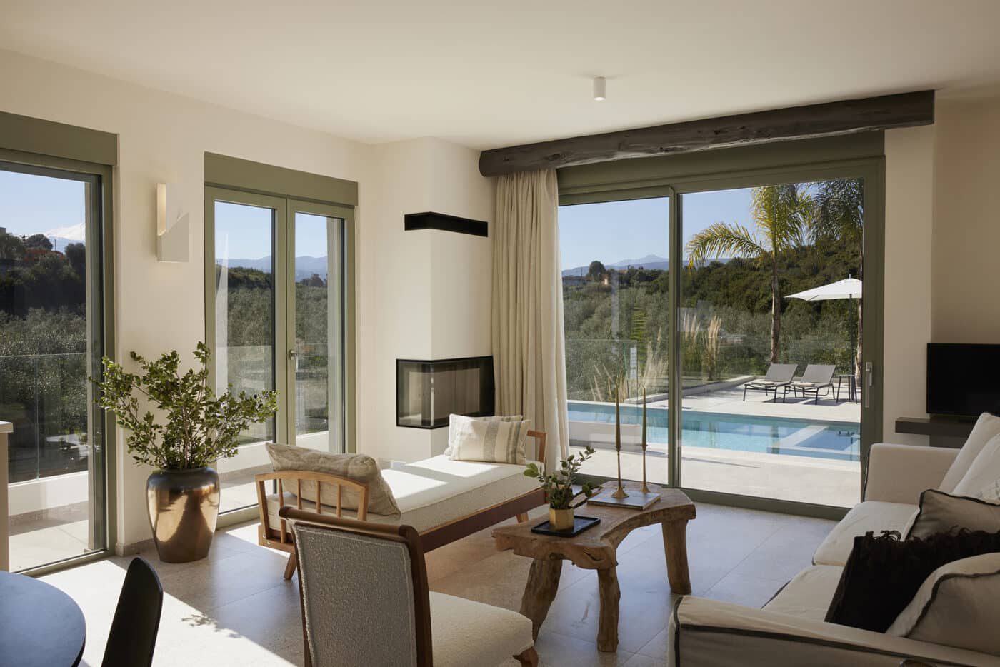 Sunlit villa living room opening onto the pool and olive grove